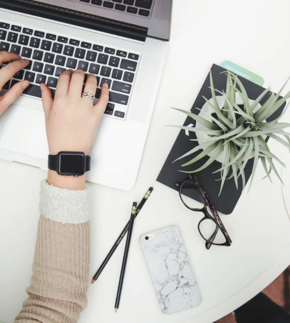 Stylish overhead shot of a desk with hands working on a laptop